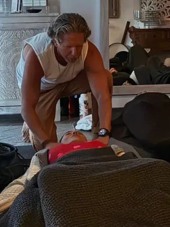 Keith kneeling beside a participant lying under a blanket during a guided breath session